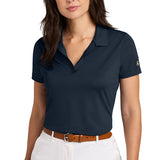 Woman wearing a dark navy buttonless polo shirt paired with white pants and a brown belt