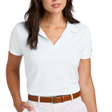 Woman wearing a white buttonless polo shirt paired with white pants and a brown belt